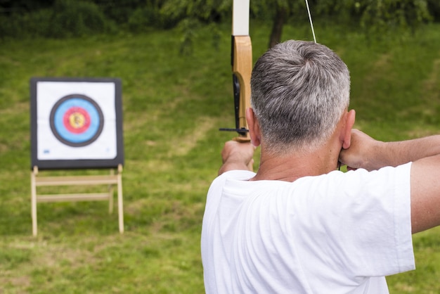 Man holding the arrow and playing the target archery game