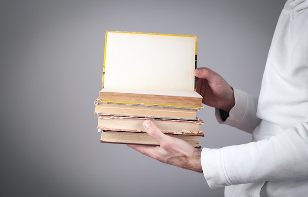 Man holding books on grey background.