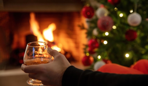 Man holding a brandy glass burning fireplace and Christmas tree background