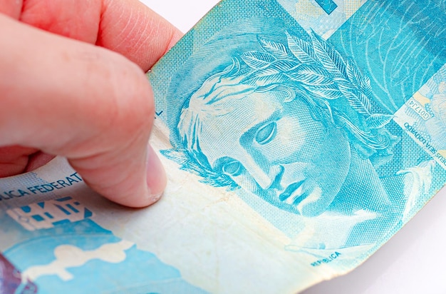 A man holding a brazilian banknote of 100 reais