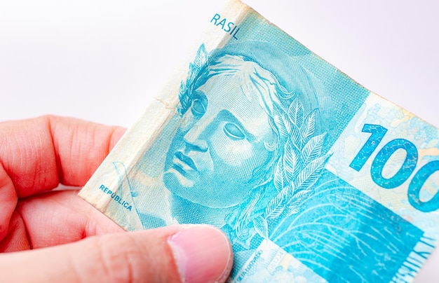 A man holding a brazilian real banknote of 100 reais