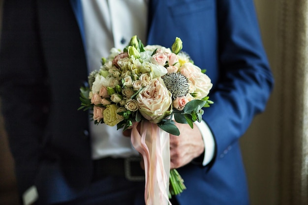 Man holding bridal bouquet in hands groom getting ready in the morning before wedding ceremony