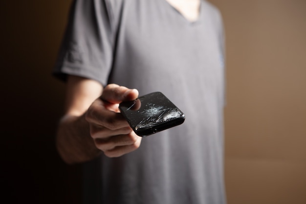 Man holding broken phone on brown background