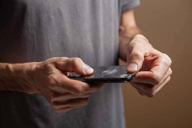 Man holding broken phone on brown background