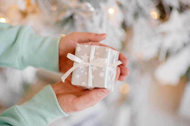 man holding christmas gift box on bokeh lights