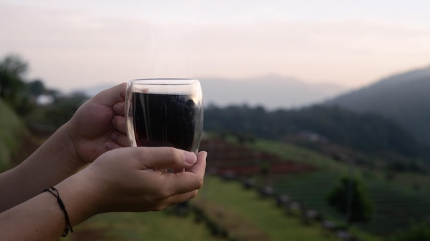 Man holding coffee cup with blurred natural mountain view in background