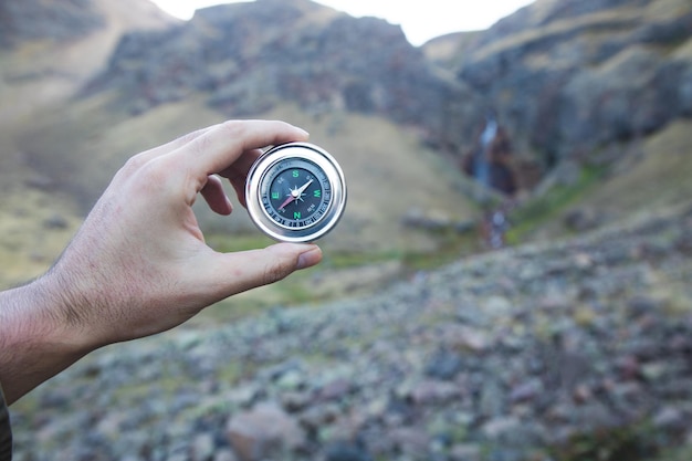 Man holding a compass on a mountain background