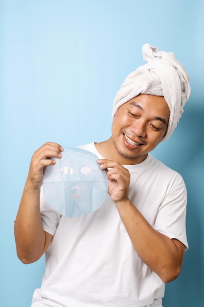 Man holding cosmetics mask on blue background Beauty and Skin care concept