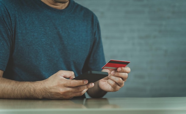 Man holding credit card and using laptop computer Businessman working at home Online shopping ecommerce internet banking spending money working from home concept