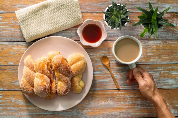 A man holding a cup of black coffee and a glass of orange juice Croissants bread