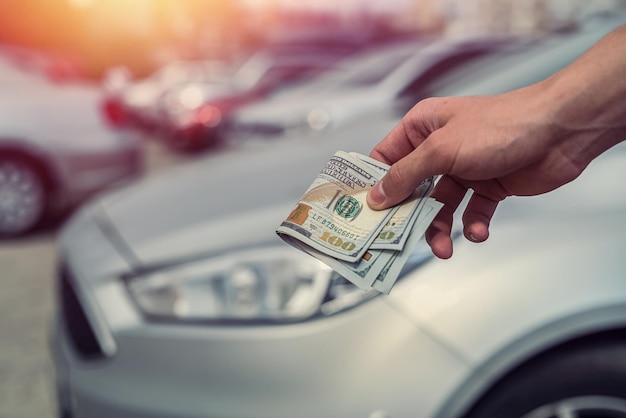 Man holding dollars for buying new modern car. paying