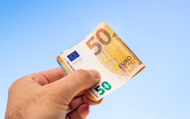 a man holding Euro banknotes with blue sky background