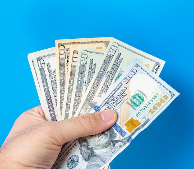 a man holding fanshaped us dollar bills with blue background 