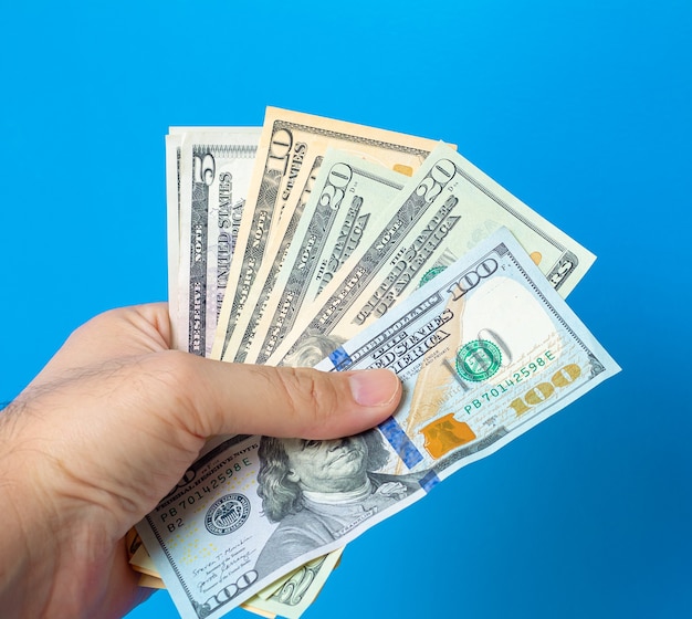 a man holding fanshaped us dollar bills with blue background 