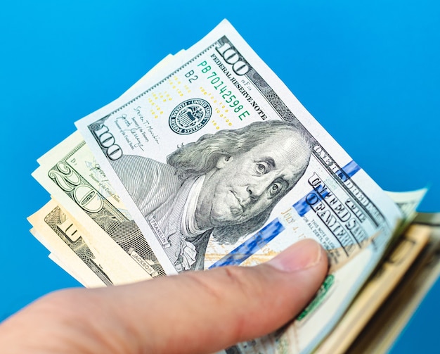 a man holding fanshaped us dollar bills with blue background 