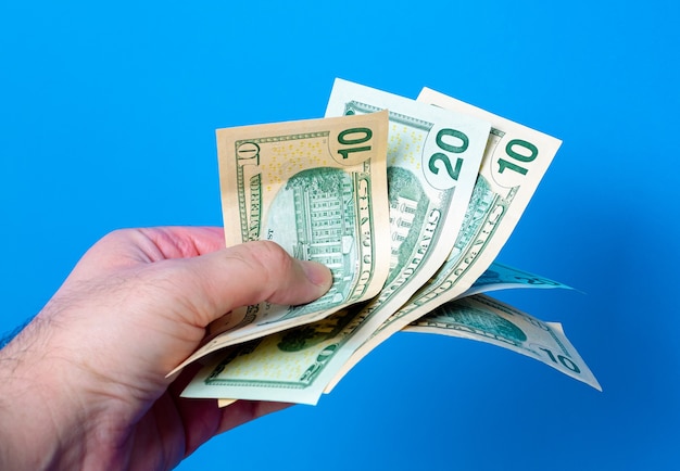 a man holding fanshaped us dollar bills with blue background 