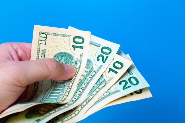 a man holding fanshaped us dollar bills with blue background 