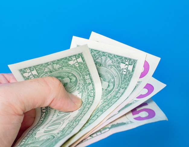 a man holding fanshaped us dollar bills with blue background 