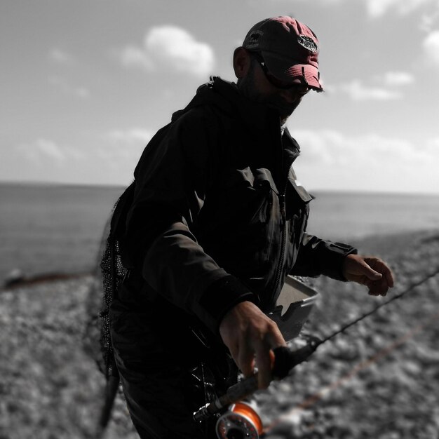 Photo man holding fishing rod at beach