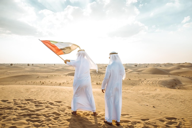 Photo man holding flag on sand dune against the sky