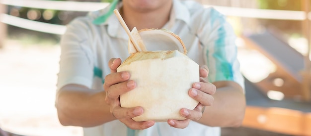 Man holding fresh coconut juice during drinking on tropical beach Summer relaxing and vacation concepts