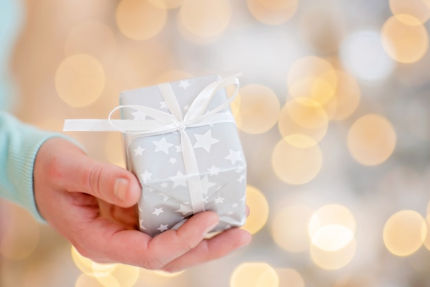 man holding gift in his hand on bokeh background