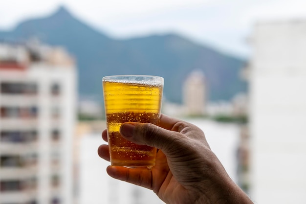 Man holding glass of beer on blurred urban city background