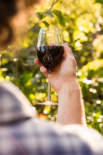 Man holding a glass of red wine in the garden