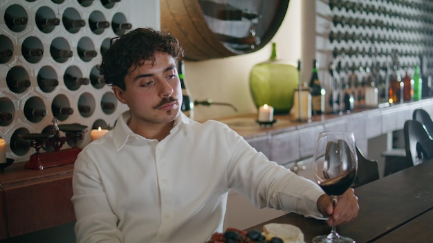 Man holding goblet wine sitting in cozy restaurant close up italian sommelier