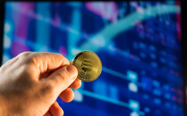 Man holding a golden Solana coin with the financial stock market graph in the background Cryptocurrency coin Financial market