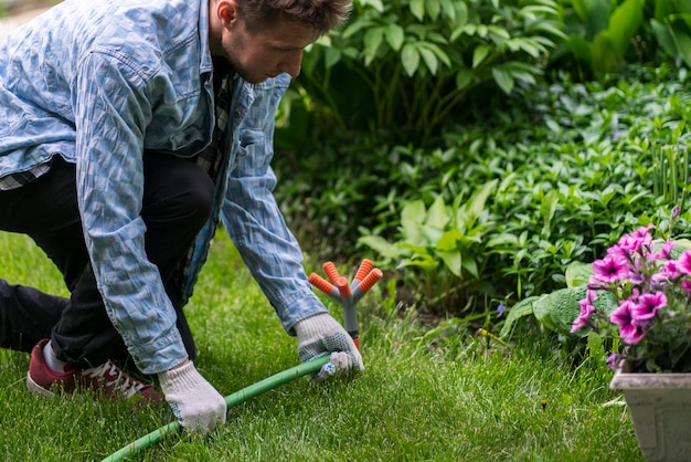 A man holding a grass water sprinker and adjusting the atomatic watering system