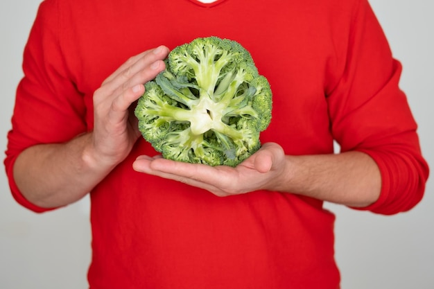 Man holding green fresh broccoli isolated on white background