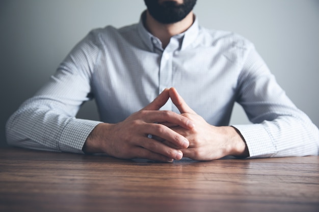 Man holding hands crossed on desk