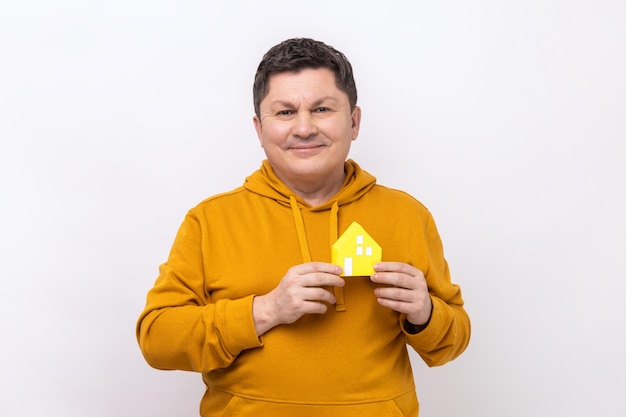 Man holding in hands and showing paper model of house of his dream real estate agency advertisement