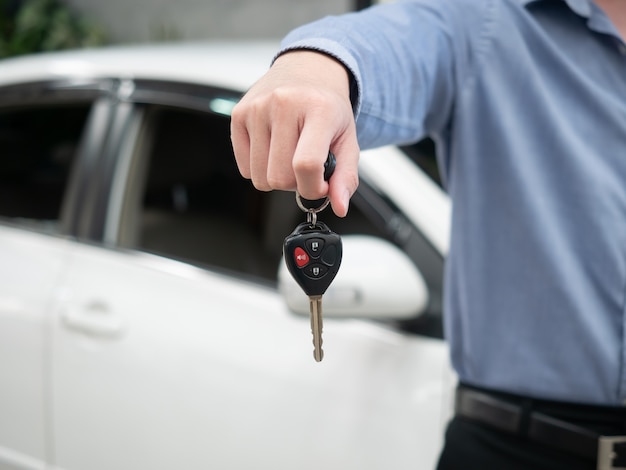 Man holding key in modern auto dealership. Close up hand of cardealer giving car key to customer