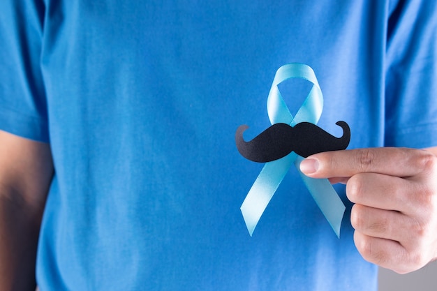 Man  holding light blue ribbon with mustache.