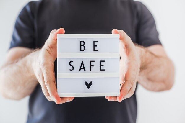 Man holding lightbox with text Be safe