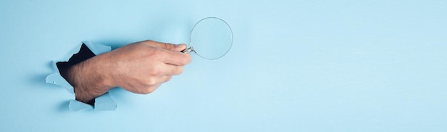 Man holding maginfier on blue background