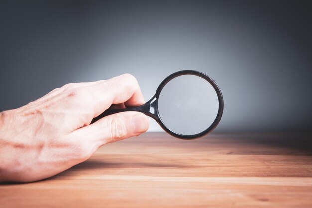 Photo man holding a magnifying glass in his hands search for information