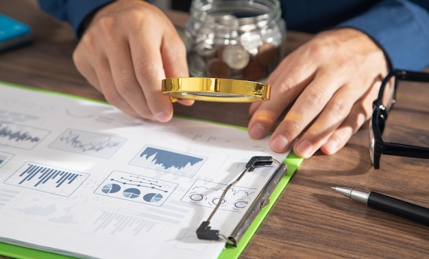 Man holding magnifying glass with a graphs and charts Business Analysis