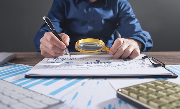 Photo man holding magnifying glass with a graphs and charts. business. analysis