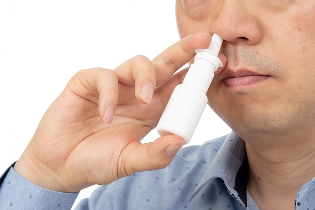 A man holding a nasal spray in his hand on white 