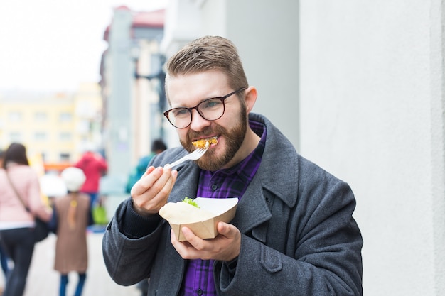 Man holding one-off plate with traditional delicious jewish food falafel made of chickpeas at the street food festival.