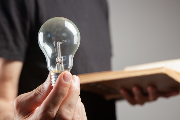 Man holding an open book and a light bulb. concept idea from a book