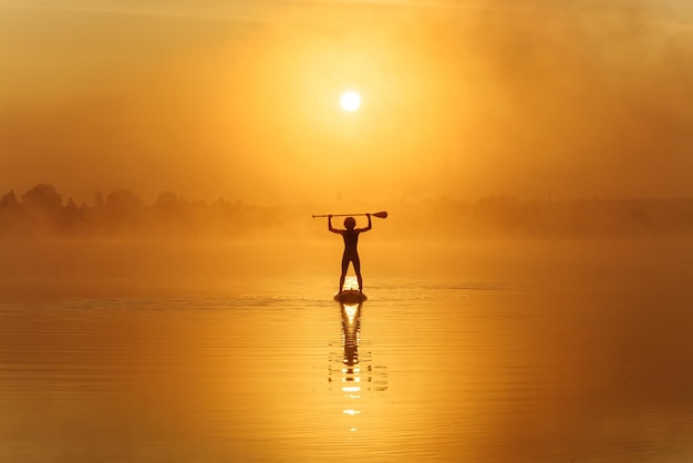 Man holding paddle above head while standing on sup board