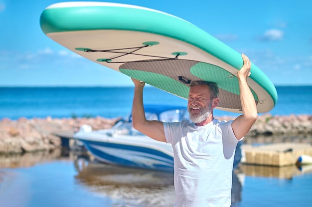 Man holding paddleboard on his head looking away