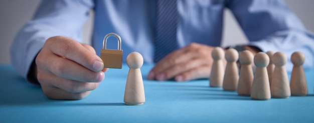 Man holding padlock Human wooden figures on the desk Personal protection