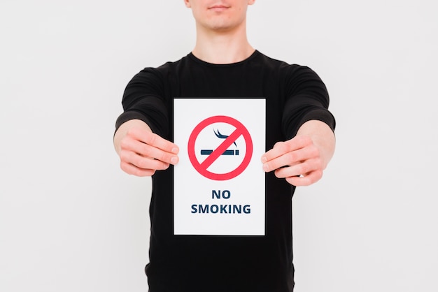 Photo man holding paper with no smoking text and sign on white wall