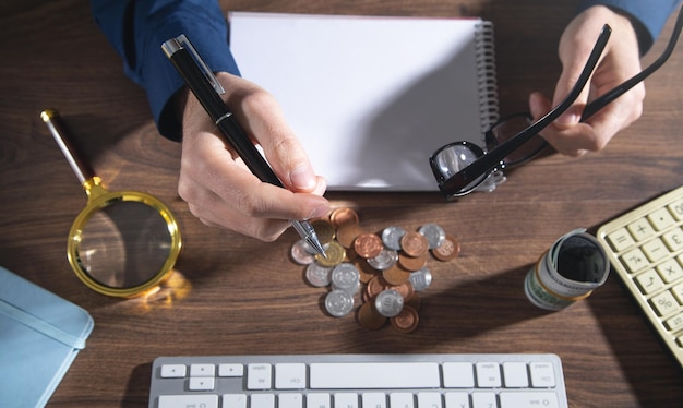 Man holding pen with a counting coins on the desk