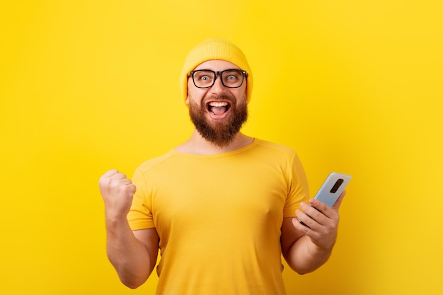 Man holding phone over yellow background, winner concept